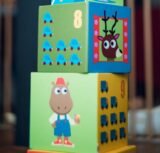 A child playing indoors, stacking colorful wooden toy blocks with joyful illustrations.